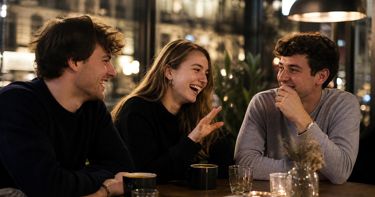 Three international university friends laughing together in a Warsaw cafe
